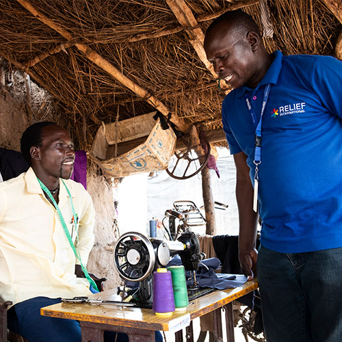 Relief International project officer Yones Simon (right) visits Sebit Anguk, 24, a member of a Village Savings and Loan Association (VSLA) in Batil refugee camp, South Sudan. Elie Gardner/RI