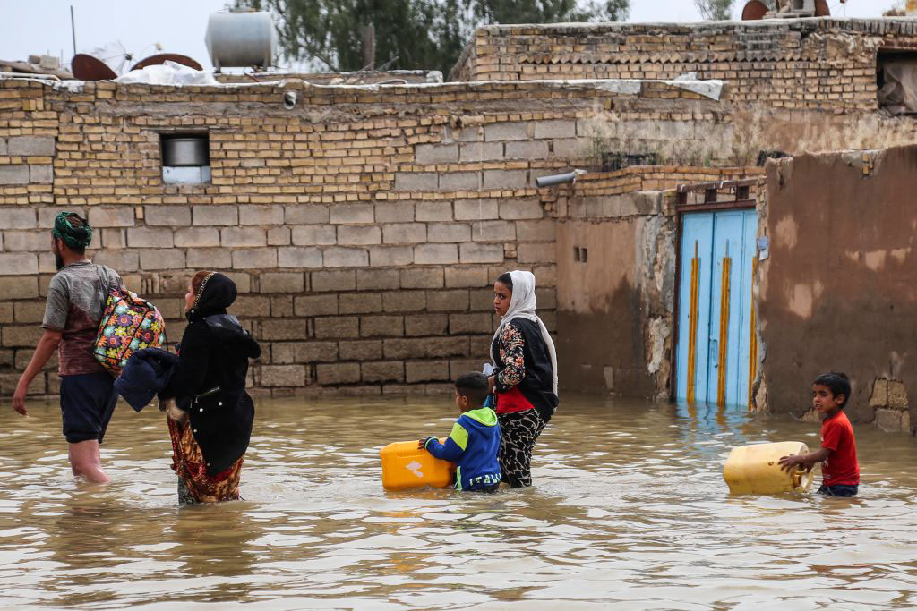 An Iranian family walks through a flooded street in a village around the city of Ahvaz, in Iran's Khuzestan province, on March 31, 2019. Mehdi Pedramkhoo/AFP/Getty Images