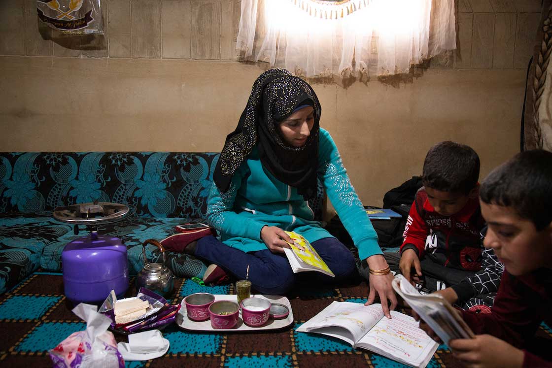 Iman sits with her children as they complete their homework in the morning. Elie Gardner/RI