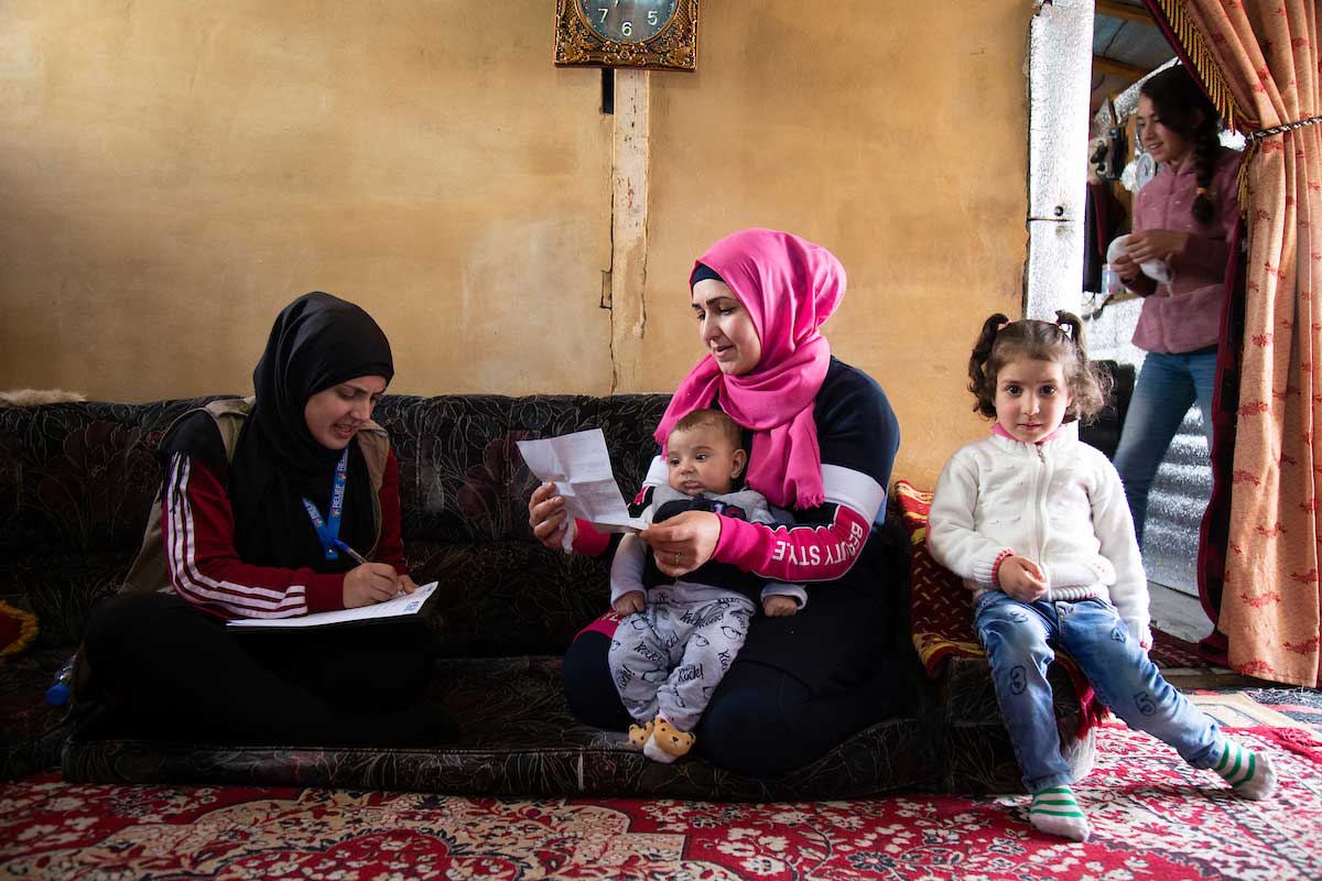 Relief International Social Worker Fatima Abdul Wahed meets with Asmaa at her home as her seven young children crowd around her. Elie Gardner/RI