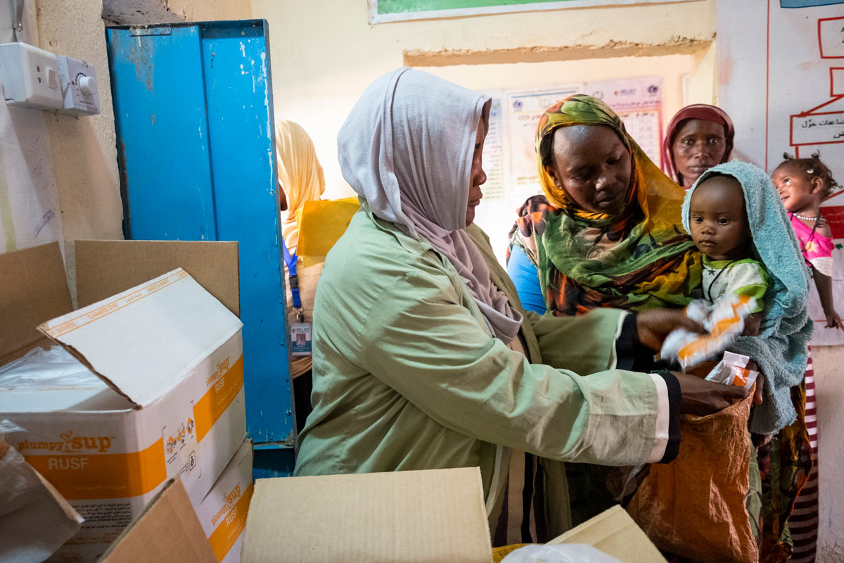 Women line up at Relief International's clinic in Zamzam A during a monthly distribution of Plumpy'Nut, a leading treatment for severe acute malnutrtion. Women line up at Relief International's clinic in Zamzam A during a monthly distribution of Plumpy'Nut, a leading treatment for severe acute malnutrtion.