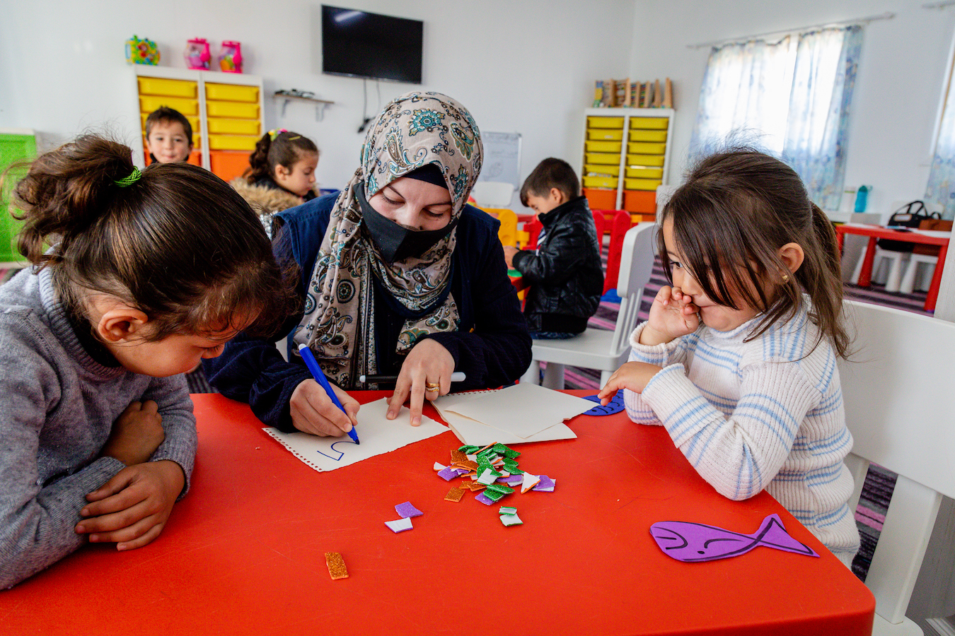 Suzan-teaching-ECD-Azraq-Camp-center-children-Arabic-letters-and-her-daughter-Sham-next-to-her-2.jpg